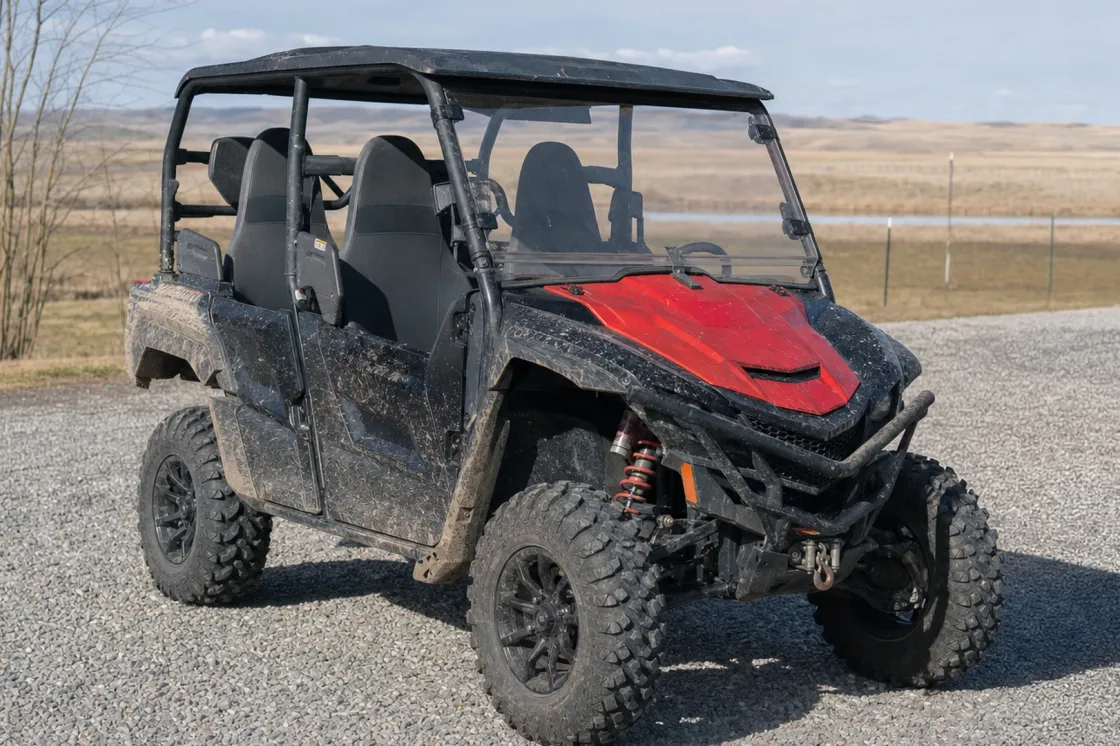 A used side-by-side vehicle parked on a gravel pad in rural Alberta with open prairie and distant foothills