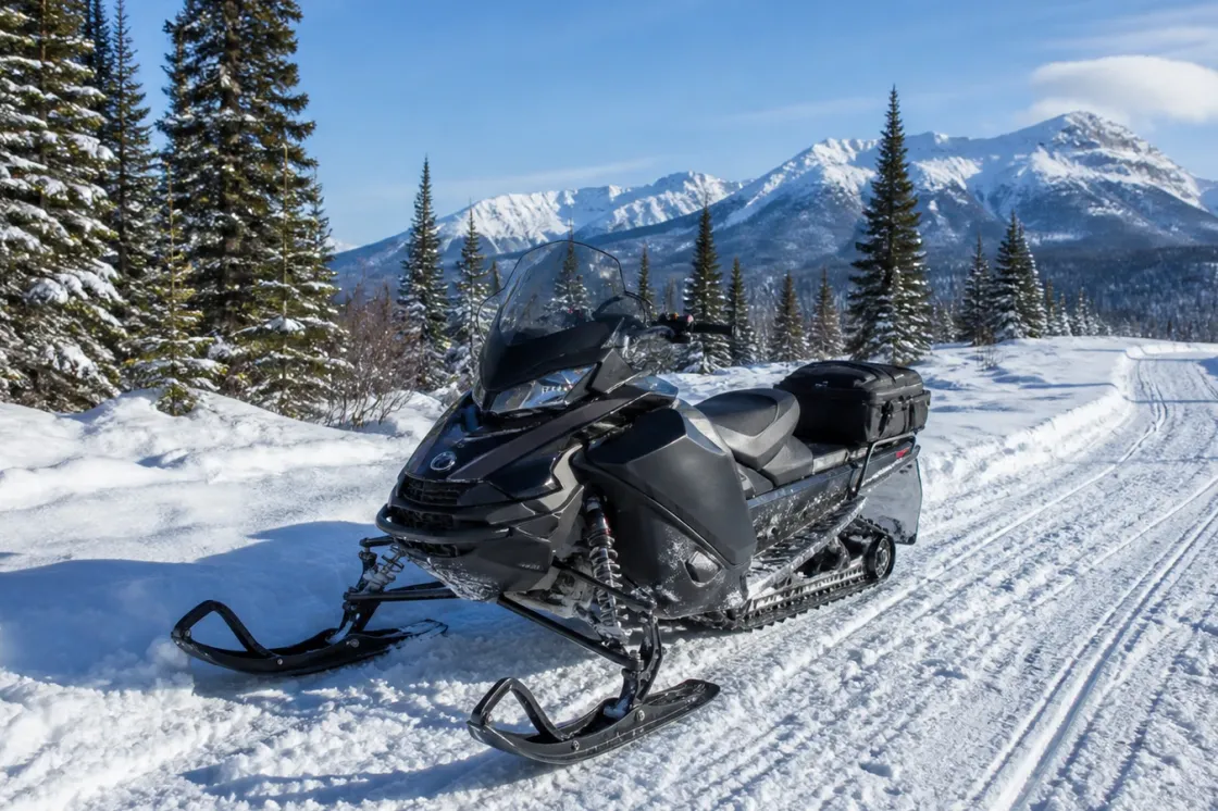 Pre-owned modern snowmobile parked on a winter snowpack trail in Alberta under clear blue sky